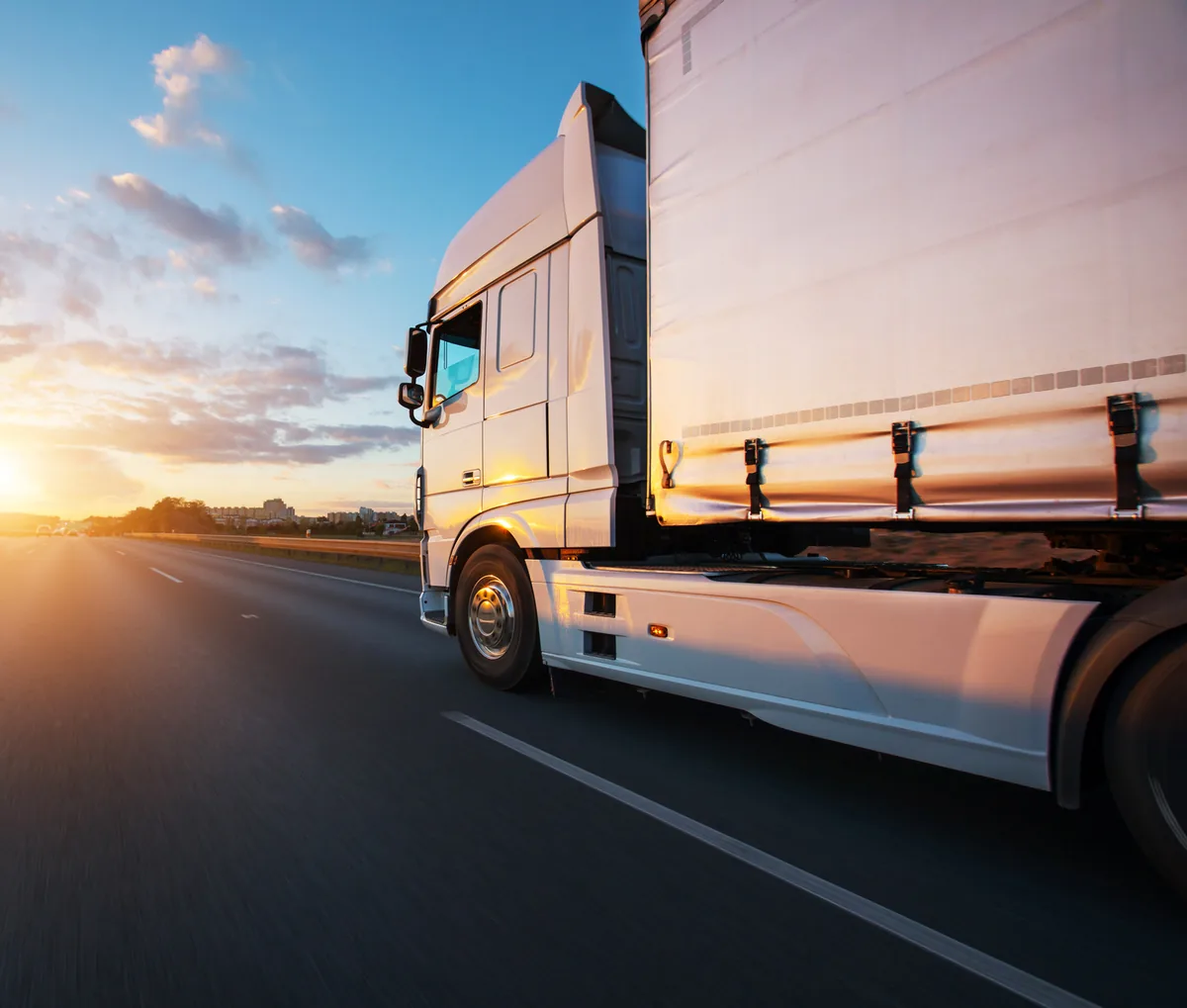 Ein weißer Lkw auf der Autobahn bei Sonnenuntergang