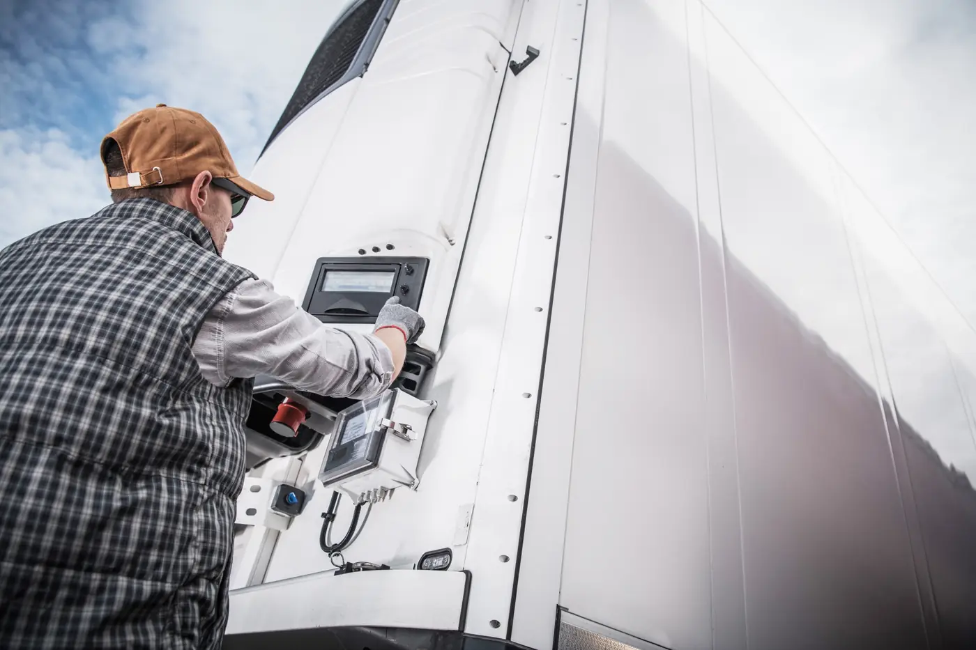 Ein Fahrer stellt die Temperatur am Kühlaggregat eines Lkw-Aufliegers ein